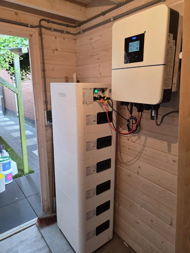 Deye inverter in a timber garden shed next to a tall Dyness battery stack.