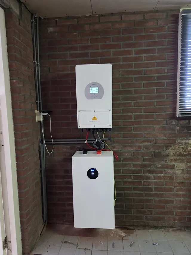 Deye inverter with one battery module against a brick wall.